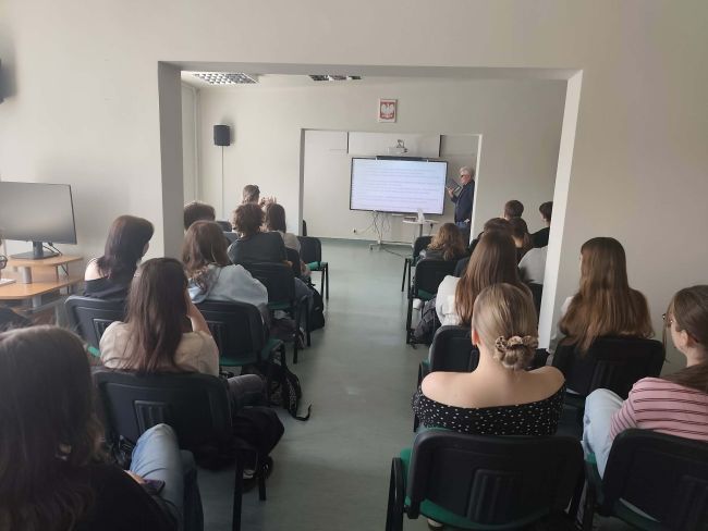 uczniowie siedzący na krzesłach oglądają zdjęcie wyświetlone zdjęcie